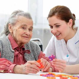 professional nurse helping old woman with a puzzle